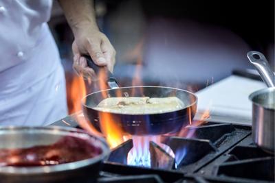 Chef en train de faire cuire un plat sur sa taque de cuisson au gaz de propane.